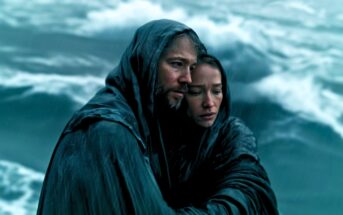 Two people huddled together in rain-soaked cloaks, standing near rough ocean waves, looking weary and solemn as they seek comfort from each other amid the storm.