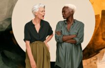 An older person with white hair yells at another older person with short light hair, who stands with arms crossed, looking displeased. Both wear casual shirts, standing in front of an abstract background.