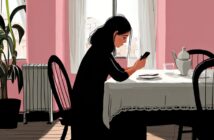 A woman sits alone at a table in a pink-walled room, looking at her phone. A teapot, cup, and plate are on the table. Sunlight streams through the window behind her.