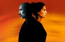 A man and woman stand back-to-back against a warm gradient background, with the man’s side in cool tones and the woman’s side in warm tones, symbolizing contrast or duality.
