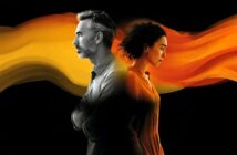 A man and a woman stand back to back, both looking serious. An orange-yellow swirling streak flows between and behind them against a black background.
