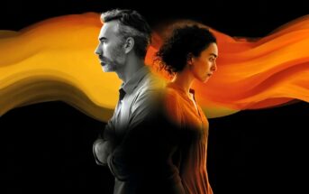 A man and a woman stand back to back, both looking serious. An orange-yellow swirling streak flows between and behind them against a black background.