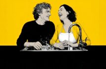 A man and woman laugh together while washing dishes at a sink, splashing water. The background is bright yellow, and both appear joyful and relaxed.
