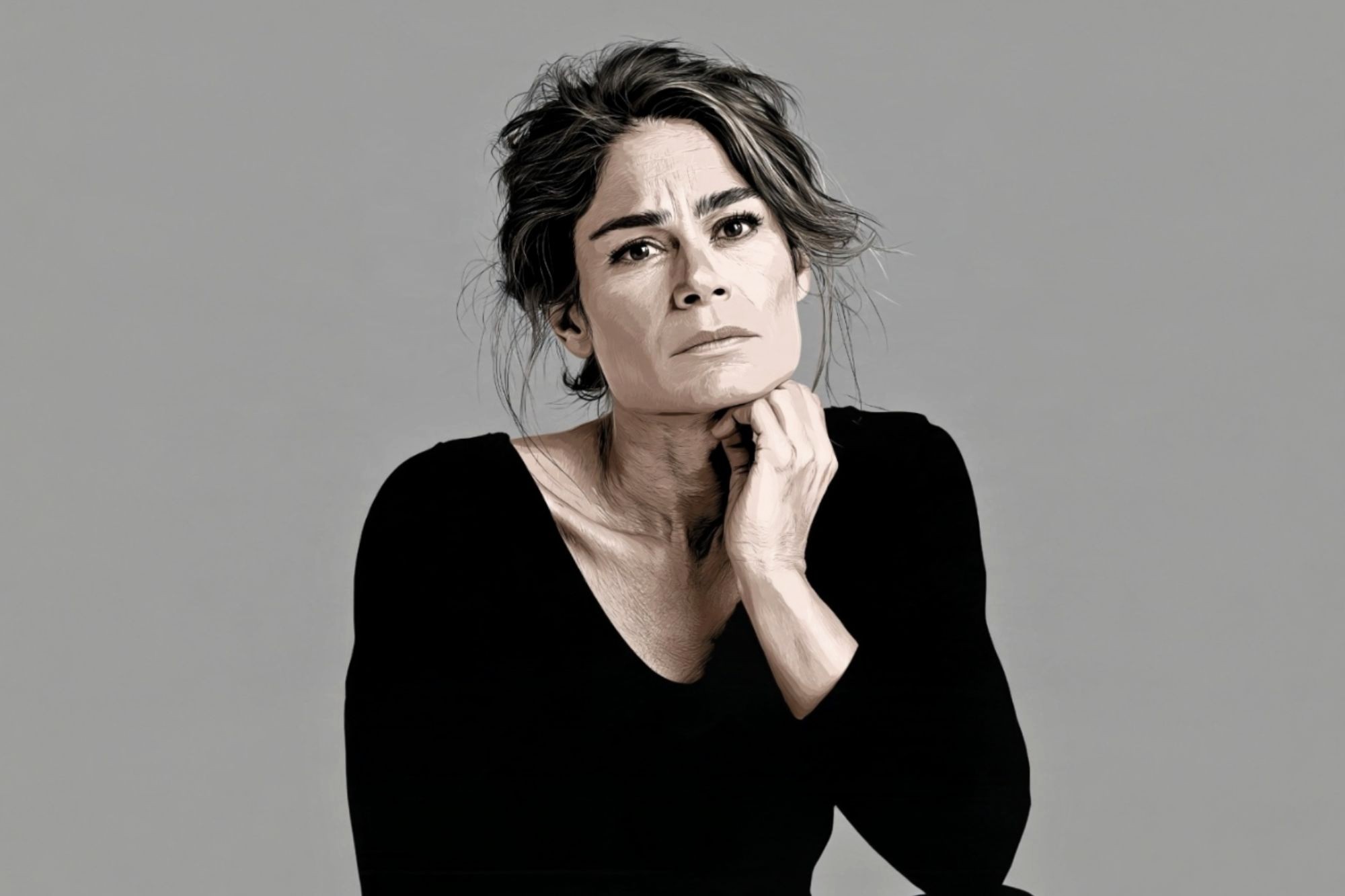 A portrait of a woman in a black long-sleeved shirt with her hand resting under her chin, looking directly at the camera.