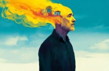 A man stands in profile; the top of his head transitions into a vibrant yellow and orange burst, with small houses and birds emerging from the colors, symbolizing imagination or memory.