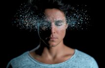 A person with closed eyes, surrounded by a cloud of glowing, digital-looking light particles emanating from their face.