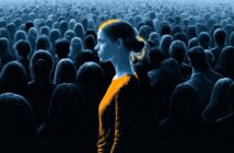 A young woman in a glowing orange shirt stands in profile amidst a vast, dimly lit crowd of people shown in silhouette.