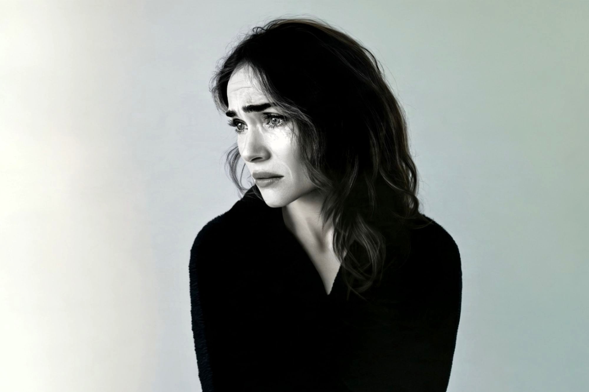 A woman looking away with a tearful, distressed expression.