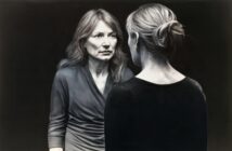 A woman with long hair looking at her own reflection in a mirror.